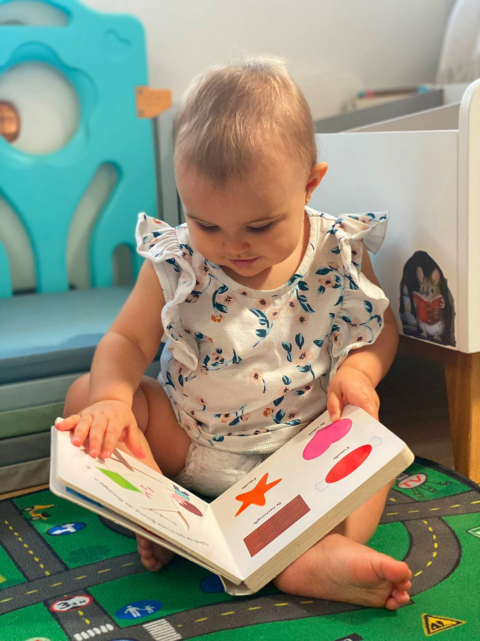 Elyana participe au concours pour gagner de l'argent avec cette photo : arm, baby, baby_playing_with_toys, baby_toddler_clothing, blue, book, child, dress, flooring, fun, gadget, green, hand, head, kitchen_appliance, person, publication, room, sitting, smile