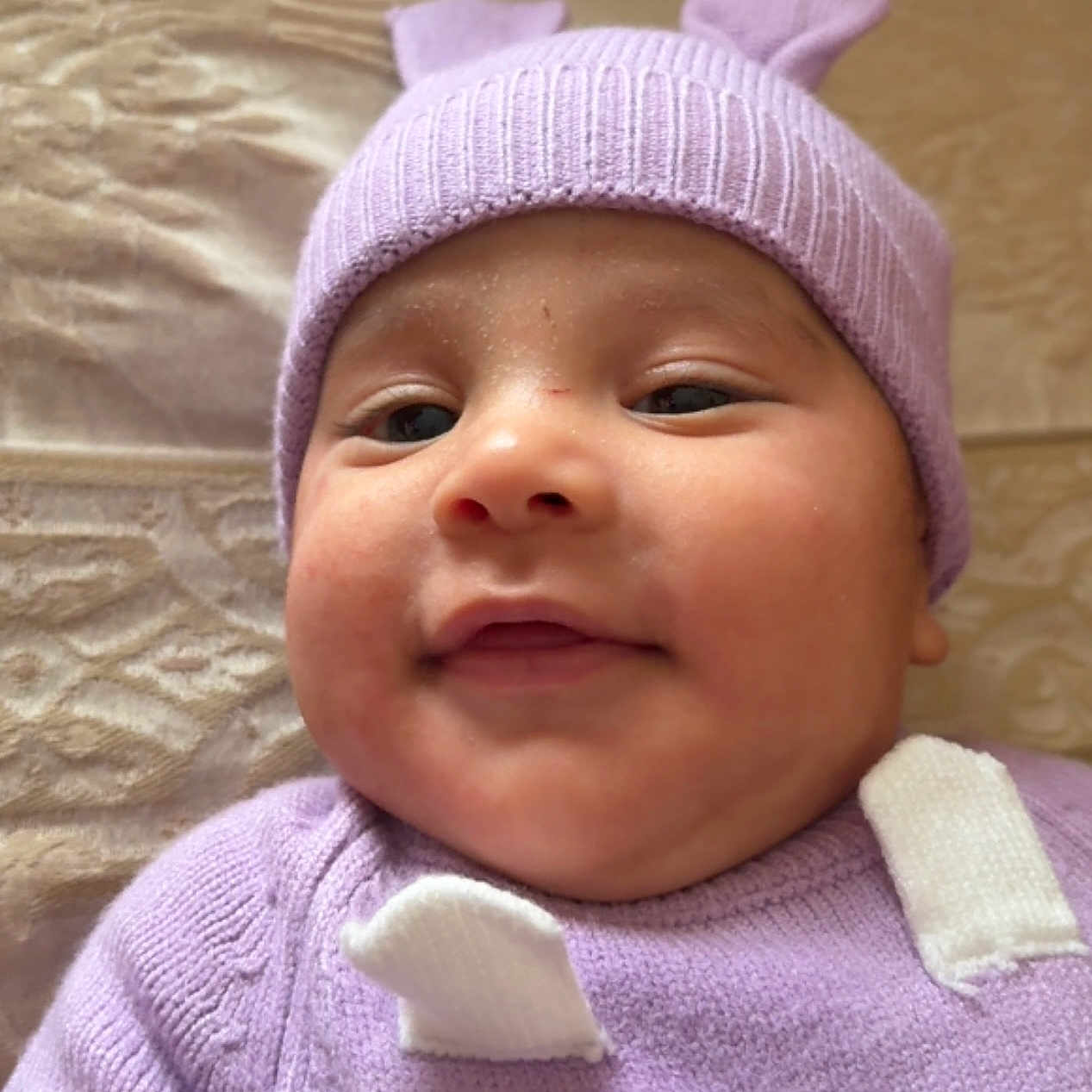 Dylan Andrés joined the competition — help win amazing prizes! baby, blanket, cheeks, child, closeup, clothing, cozy, cute, face, happy, hat, indoors, infant, knitwear, lying_down, portrait, purple, smile, soft_texture, warm