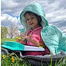 Sriaadhya is registered to the contest to win money with this photo: blanket, casual_clothing, child, cloudy_sky, curious, dandelions, daytime, grass, greenery, hood, jacket, nature, outdoor, person, play, portrait, sitting, smiling, toy, young_child