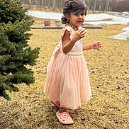 Sriaadhya joined the competition — help win amazing prizes! background, casual_footwear, child, curly_hair, daylight, dress, earrings, expression, girl, grass, nature, outdoor, person, pine_tree, pink_crocs, portrait, seasonal, standing, winter, young