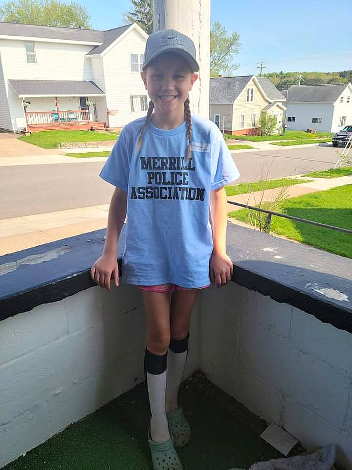 Lily is registered to the contest to win money with this photo: asphalt, baseball_cap, cap, electric_blue, fun, grass, hat, headwear, human_leg, joy, knee, leisure, person, plant, sky, sleeve, smile, sportswear, sun_hat, t_shirt