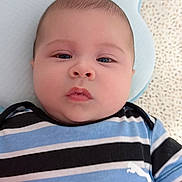 Dylan Lamas joined the competition — help win amazing prizes! baby, infant, child, portrait, lying_down, striped_shirt, blue_clothing, pillow, blanket, indoor, close_up, face, eyes, serious_expression, calm, cozy, soft_lighting, bedding, photography, cute