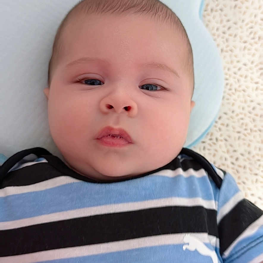Dylan Lamas joined the competition — help win amazing prizes! baby, infant, child, portrait, lying_down, striped_shirt, blue_clothing, pillow, blanket, indoor, close_up, face, eyes, serious_expression, calm, cozy, soft_lighting, bedding, photography, cute