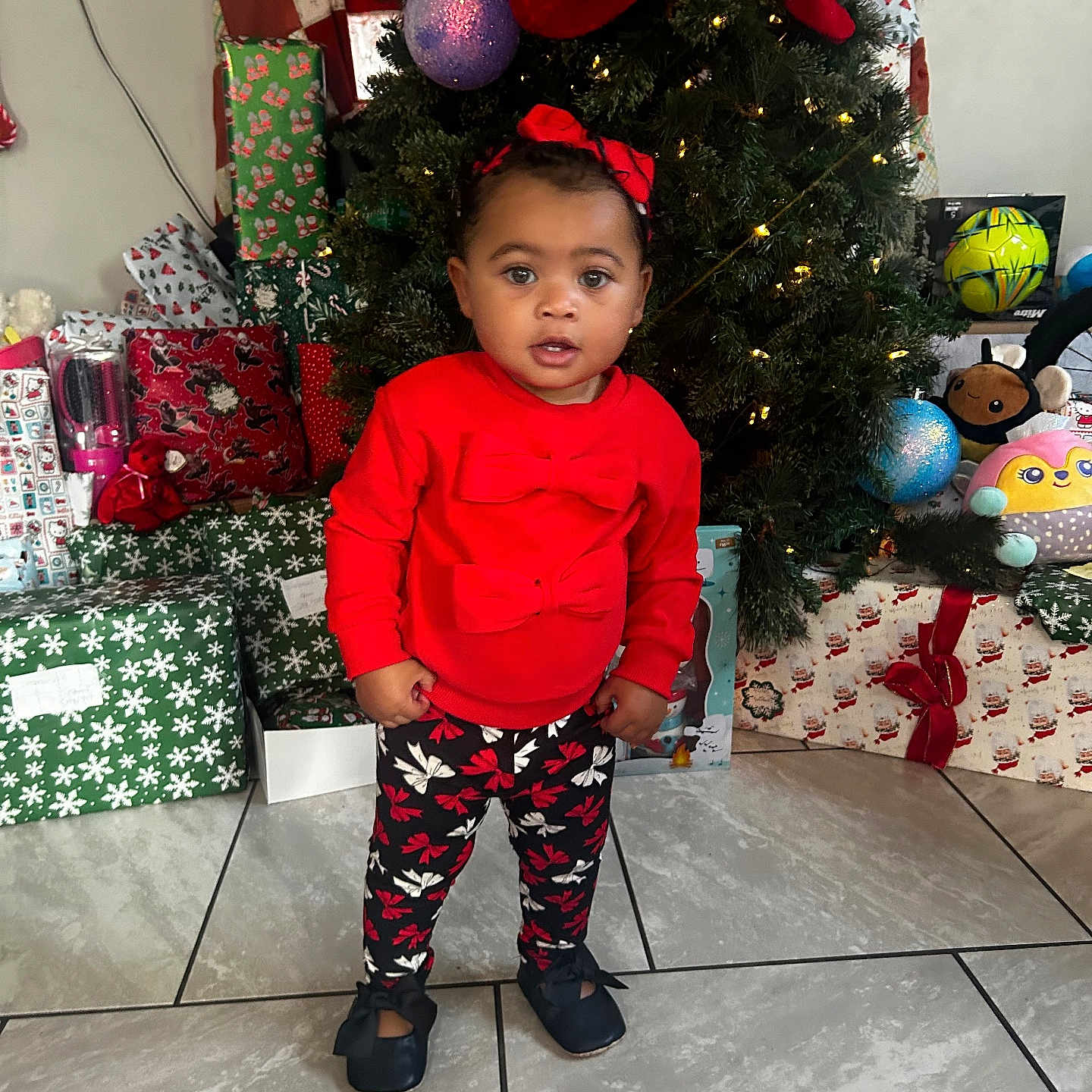 Patience joined the competition — help win amazing prizes! bow, celebration, child, christmas_tree, cute, decorations, festive, floor_tiles, gift_wrap, holiday, holiday_lights, home, indoor, patterned_pants, portrait, presents, red_sweater, shoes, smiling, toddler