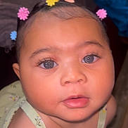 Patience is registered to the contest to win money with this photo: baby, baby_clothes, child, closeup, colorful, curious, cute, expression, eyes, face, flower_clips, hair_accessories, indoors, infant, looking, person, portrait, skin, soft_lighting, young_child