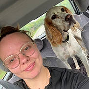 Usko a rejoint le concours — aidez-le/la à gagner de superbes lots ! black_shirt, car_interior, casual, daylight, dog, glasses, greenery, indoor, long_ears, necklace, person, pet, portrait, road, seat, seatbelt, smile, spotted_dog, travel, window