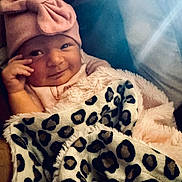 Alessia is registered to the contest to win money with this photo: baby, child, blanket, pink_hat, leopard_print, smile, portrait, cute, infant, clothing, face, hand, cozy, warm, indoor, person, headwear, soft, adorable, newborn