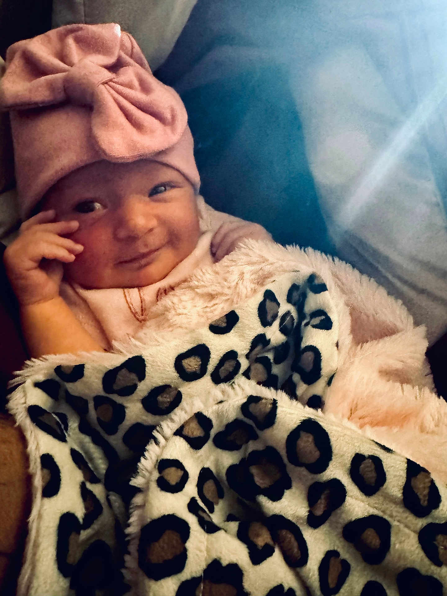 Alessia is registered to the contest to win money with this photo: baby, child, blanket, pink_hat, leopard_print, smile, portrait, cute, infant, clothing, face, hand, cozy, warm, indoor, person, headwear, soft, adorable, newborn