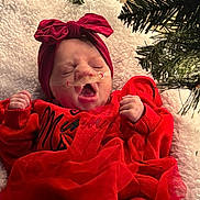 Rayne joined the competition — help win amazing prizes! baby, infant, red_clothing, headband, yawning, christmas_tree, holiday, festive, blanket, tulle_skirt, cozy, indoors, sleepy, cute, newborn, face, person, celebration, decorations, festivity