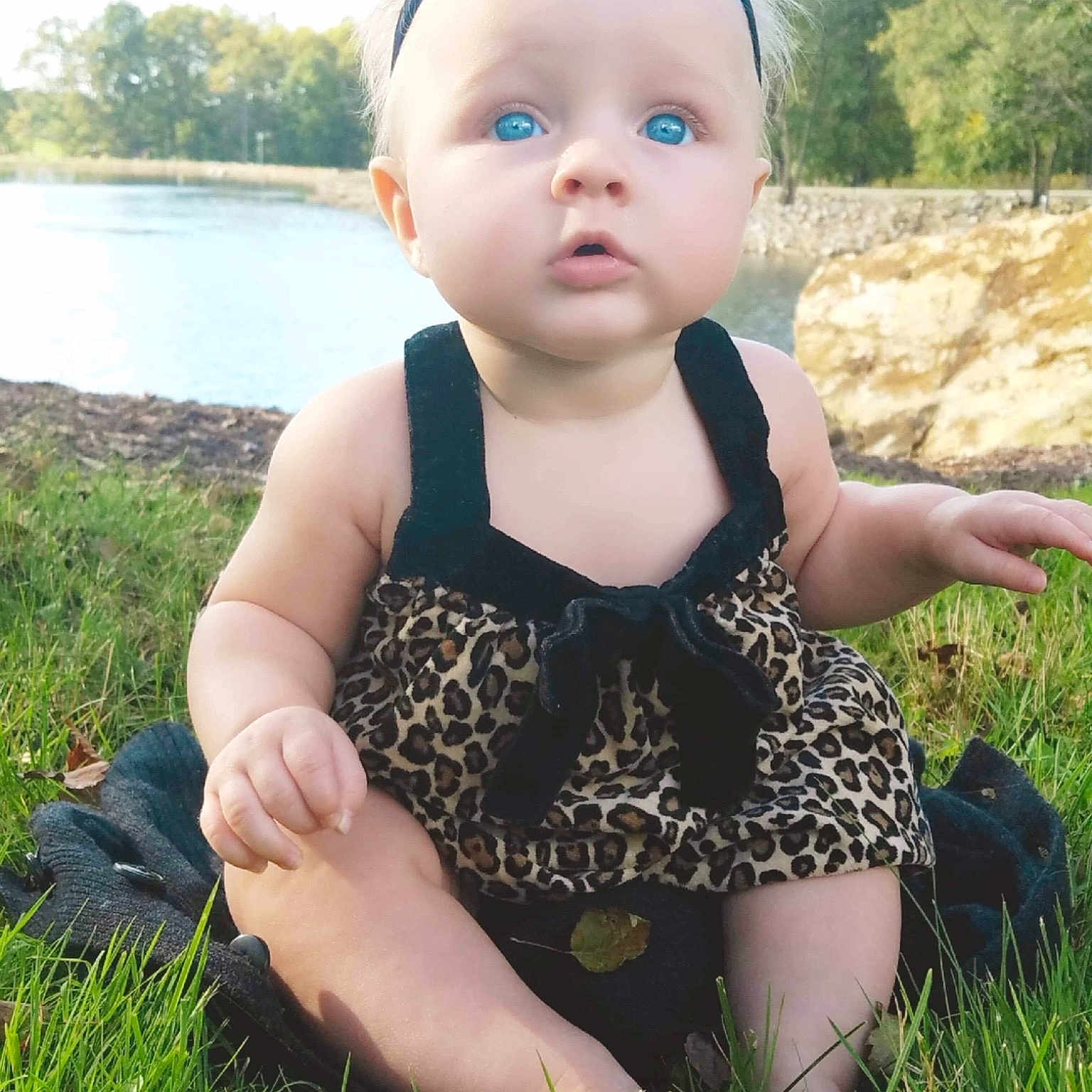 Makayla is registered to the contest to win money with this photo: baby, baby_toddler_clothing, child, dress, face, fawn, grass, grass_family, head, meadow, pattern, person, plant, sitting, skin, smile, summer, toddler