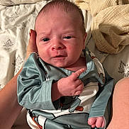 Jace joined the competition — help win amazing prizes! baby, infant, hand, clothing, bed, blanket, person, face, expression, sleepwear, newborn, skin, human, cute, lying_down, comfort, indoor, young_child, holding, gesture
