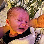 Jace is registered to the contest to win money with this photo: baby, infant, sleeping, smiling, person, face, arm, clothing, blanket, pattern, fabric, comfort, cozy, closeup, skin, head, newborn, rest, soft, indoors
