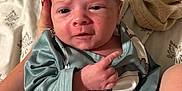 Jace is registered to the contest to win money with this photo: baby, infant, hand, clothing, blanket, bed, person, face, cute, sleepwear, newborn, expression, skin, lying_down, soft, comfort, indoors, child, portrait, sleepy