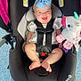 Laylah is registered to the contest to win money with this photo: baby, car_seat, blue_bow, smiling, unicorn_toy, infant, child, safety_harness, black_car_seat, happy, cute, indoors, plush_toy, footwearless, white_clothing, headband, toy, floor, person, seat