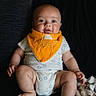 baby, infant, child, bib, orange_bib, onesie, sitting, cute, portrait, indoor, skin, face, hands, feet, expression, clothing, fabric, soft_toys, blanket, dark_background