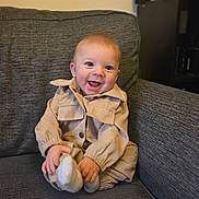 Alfie joined the competition — help win amazing prizes! baby, child, smiling, sitting, couch, clothing, beige_outfit, happy, indoors, cozy, person, face, infant, cute, hands, feet, furniture, portrait, young, warm