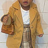 toddler, child, fashion, coat, plaid_skirt, boots, handbag, indoor, tiles, portrait, cute, brown_hair, accessories, standing, young_child, floor_mat, jewelry, white_shirt, black_tights, small_bag