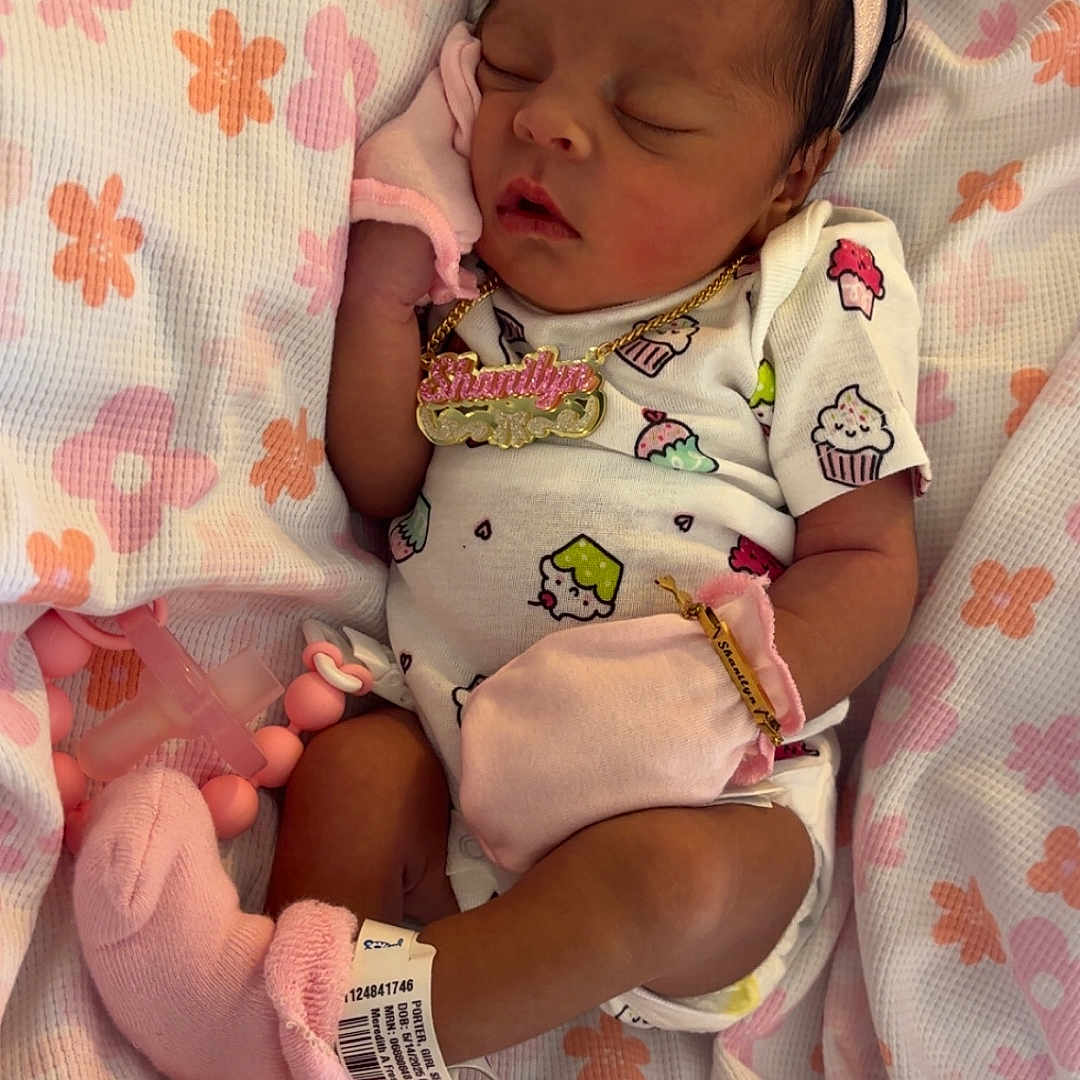 Shanilyn Jones joined the competition — help win amazing prizes! baby, blanket, bow, clothing, cozy, cute, floral_pattern, headband, indoors, infant, mittens, necklace, newborn, pacifier, pink, portrait, resting, sleeping, socks, soft