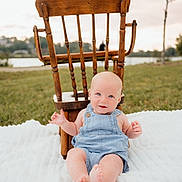 Maddox joined the competition — help win amazing prizes! baby, denim_overalls, wooden_chair, blanket, outdoor, grass, smiling, blue_eyes, infant, nature, relaxing, daylight, cute, child, portrait, summer, peaceful, playing, sitting, happy