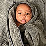 baby, blanket, wrapped, tongue_out, cute, infant, soft_texture, gray, cozy, portrait, face, head, smiling, child, newborn, expression, indoor, person, warm, comfort
