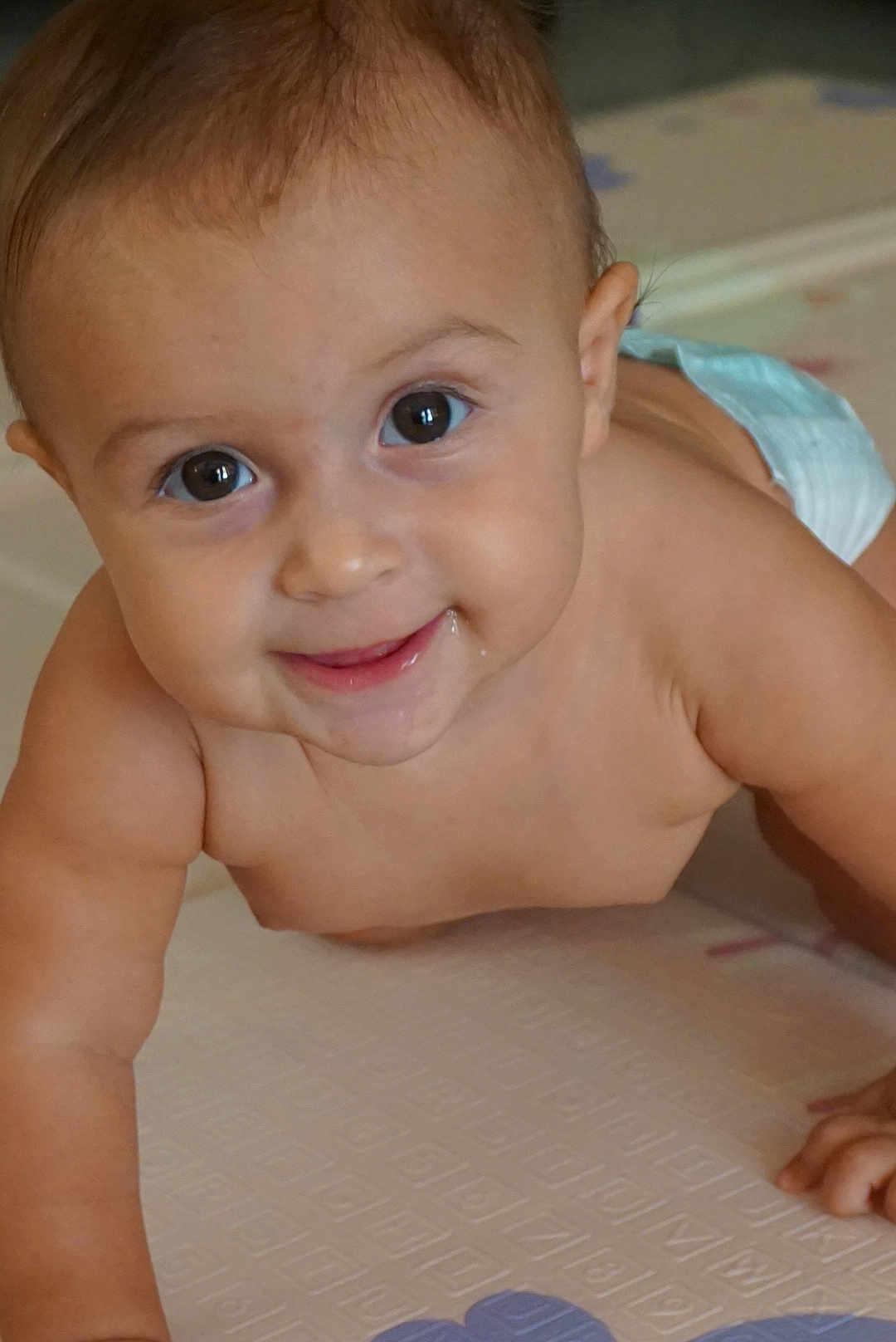 Lara participe au concours pour gagner de l'argent avec cette photo : baby, crawling, diaper, play_mat, smile, drool, face, child, infant, skin, arm, hand, eyes, cheeks, indoors, floor, cute, young, person, portrait