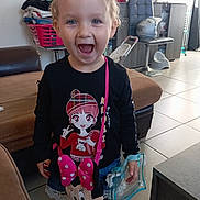 Léna participe au concours pour gagner de l'argent avec cette photo : anime_print, bag, black_shirt, cabinet, casual_clothing, chair, child, floor_tiles, furniture, happy, indoor, laundry_basket, living_room, minnie_mouse, person, potty, purse, shorts, smiling, toy