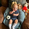 baby, child, blue_cushion, plush_toys, toy_balls, soccer_ball, basketball, football, baby_clothing, white_socks, smiling, indoor, couch, brown_couch, cute, infant, happy, portrait, seated, playtime