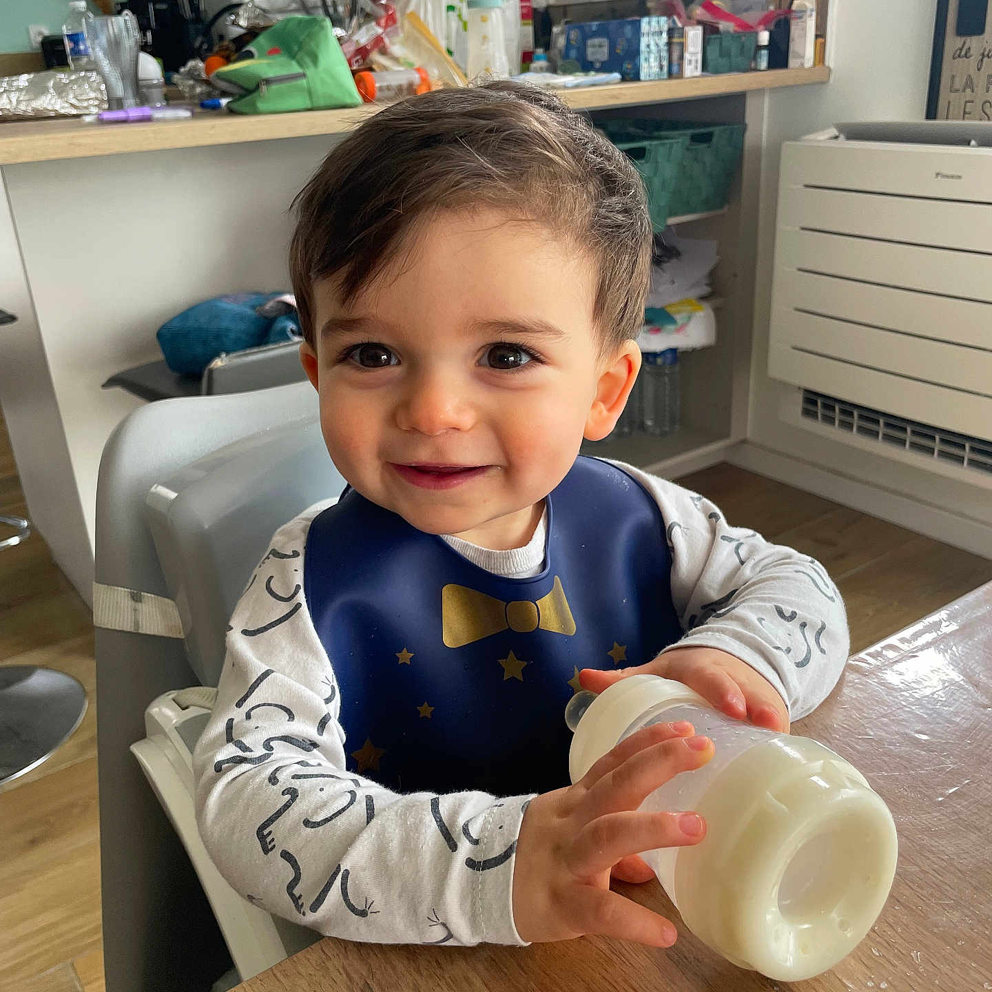 Benjamin participe au concours pour gagner de l'argent avec cette photo : accessories, baby, bag, beverage, bodypart, cup, cutlery, diningtable, face, finger, furniture, hand, handbag, head, milk, person, photography, portrait, spoon, table