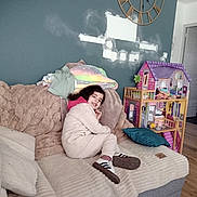 Benjamin a rejoint le concours — aidez-le/la à gagner de superbes lots ! blanket, casual_clothing, child, childhood, comfortable, cozy, dollhouse, furniture, happy, home, indoor, pillow, playroom, relaxed, smiling, sofa, toy, wall_clock, wooden_floor, young