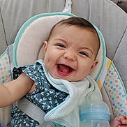Naomie a rejoint le concours — aidez-le/la à gagner de superbes lots ! baby, smiling, infant, bottle, milk, bib, seat, child, cute, happy, dimples, clothing, pattern, dragonfly, cushion, safety_belt, indoor, person, portrait, young