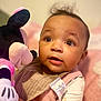 baby, child, plush_toy, minnie_mouse, pink_clothing, bib, curly_hair, wide_eyes, indoor, soft_lighting, cute, portrait, infant, toy, young_child, candid, expression, holding, warm_colors, cozy