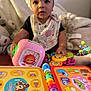 Calliah joined the competition — help win amazing prizes! baby, child, drool, bonnet, bib, toy, colorful, educational_book, indoor, curious, sitting, face, hand, play, learning, cute, infant, soft_lighting, focus, closeup