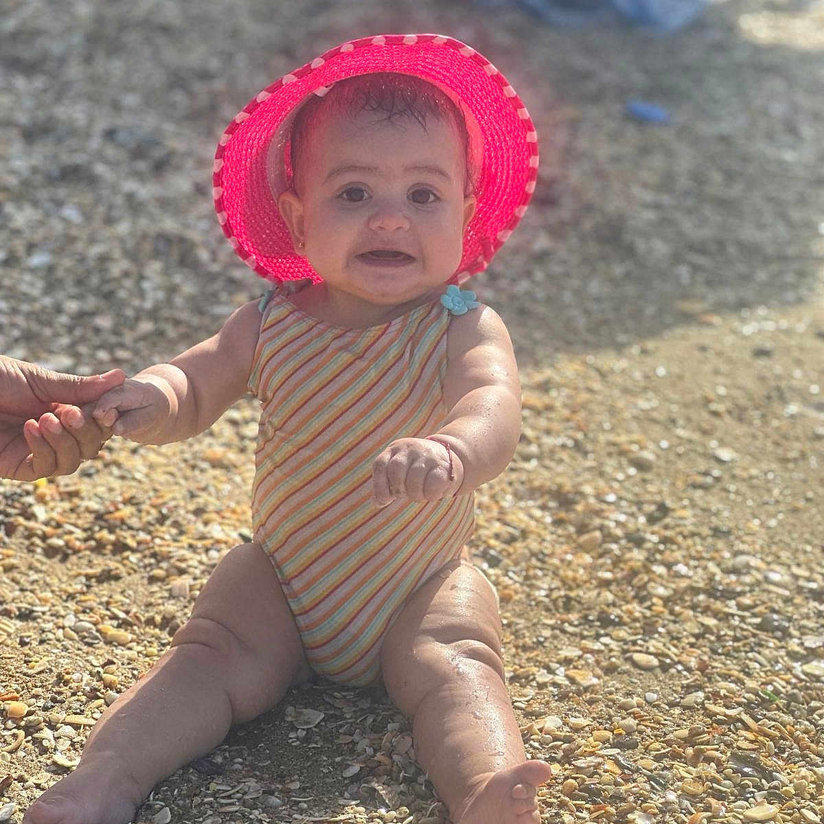 Tassneem participe au concours pour gagner de l'argent avec cette photo : baby, beach, bonnet, clothing, coast, face, hat, head, nature, outdoors, pebble, person, photography, portrait, road, rock, sea, sitting, soil, summer