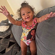 Alauni joined the competition — help win amazing prizes! toddler, child, smiling, curly_hair, swimsuit, couch, indoor, happy, arms_outstretched, cartoon_character, plush, cushion, person, home, cute, portrait, young_child, relaxed, fun, playful