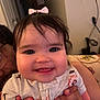 Amelia is registered to the contest to win money with this photo: baby, child, smiling, face, hand, bow, clothing, person, cute, indoor, portrait, infant, happy, skin, hair, holding, cheeks, eyes, tongue, sitting