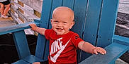 Karson joined the competition — help win amazing prizes! toddler, child, smiling, red_shirt, nike_logo, blue_chair, wooden_chair, pier, ocean, sea, sunset, outdoor, barefoot, happy, baby, person, summer, vacation, casual_clothing, water