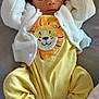 baby, sleeping, yellow_outfit, white_cardigan, lion_design, socks, infant, cozy, soft_texture, cute, relaxed, child, portrait, indoors, blanket, resting, newborn, hands_up, clothing, sleep