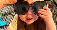 Cash joined the competition — help win amazing prizes! baby, child, sunglasses, hand, indoor, playtime, curious, expression, face, clothing, person, living_room, furniture, couch, toy, blanket, floor, skin, head, eyes