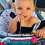 toddler, baby, child, eating, biscuit, high_chair, toy, hair_clip, smiling, face, hand, indoor, closeup, cute, playful, seat, clothing, person, infant, happy