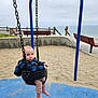 Joel joined the competition — help win amazing prizes! toddler, child, swing, playground, sand, beach, ocean, bench, jacket, blue, outdoor, daytime, sky, barefoot, fence, chain, seat, person, young, casual