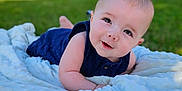 Skyler is registered to the contest to win money with this photo: baby, blanket, blue_clothing, outdoor, grass, smiling, infant, cute, portrait, face, child, soft_texture, toddler, happy, sunny, nature, head, eyes, skin, lying_down