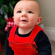 Skyler joined the competition — help win amazing prizes! baby, baby_fashion, black_shirt, child, closeup, clothing, cute, eyes, face, happy, head, indoors, infant, person, portrait, red_overall, skin, smile, warm_lighting, young