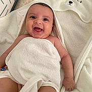 Lina participe au concours pour gagner de l'argent avec cette photo : baby, smiling, towel, hood, bunny_ears, happy, infant, skin, tongue_out, blanket, cute, lying_down, comfort, indoors, child, closeup, person, soft_texture, pillow, white
