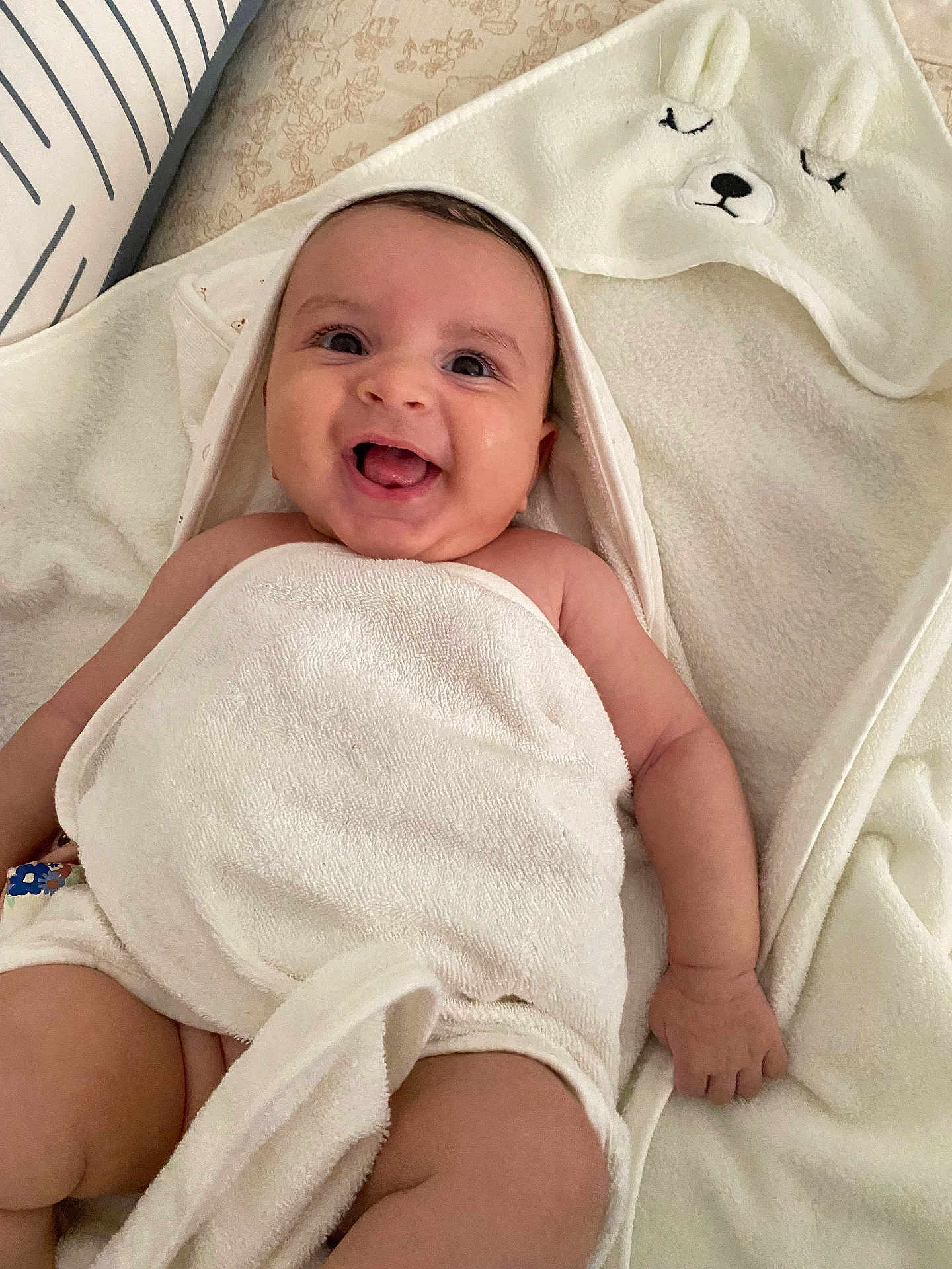 Lina participe au concours pour gagner de l'argent avec cette photo : baby, smiling, towel, hood, bunny_ears, happy, infant, skin, tongue_out, blanket, cute, lying_down, comfort, indoors, child, closeup, person, soft_texture, pillow, white