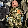 baby, infant, camouflage, onesie, blanket, pattern, smile, face, clothing, blue_mittens, lying_down, cute, cozy, soft_texture, young_child, portrait, indoor, child, person, sleepwear