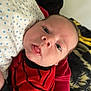 Asher is registered to the contest to win money with this photo: baby, infant, face, red_clothing, blanket, blue_dots, lying_down, closeup, curious_expression, indoors, soft_texture, young_child, person, head, skin, eyes, mouth, nose, black_stripes, fabric
