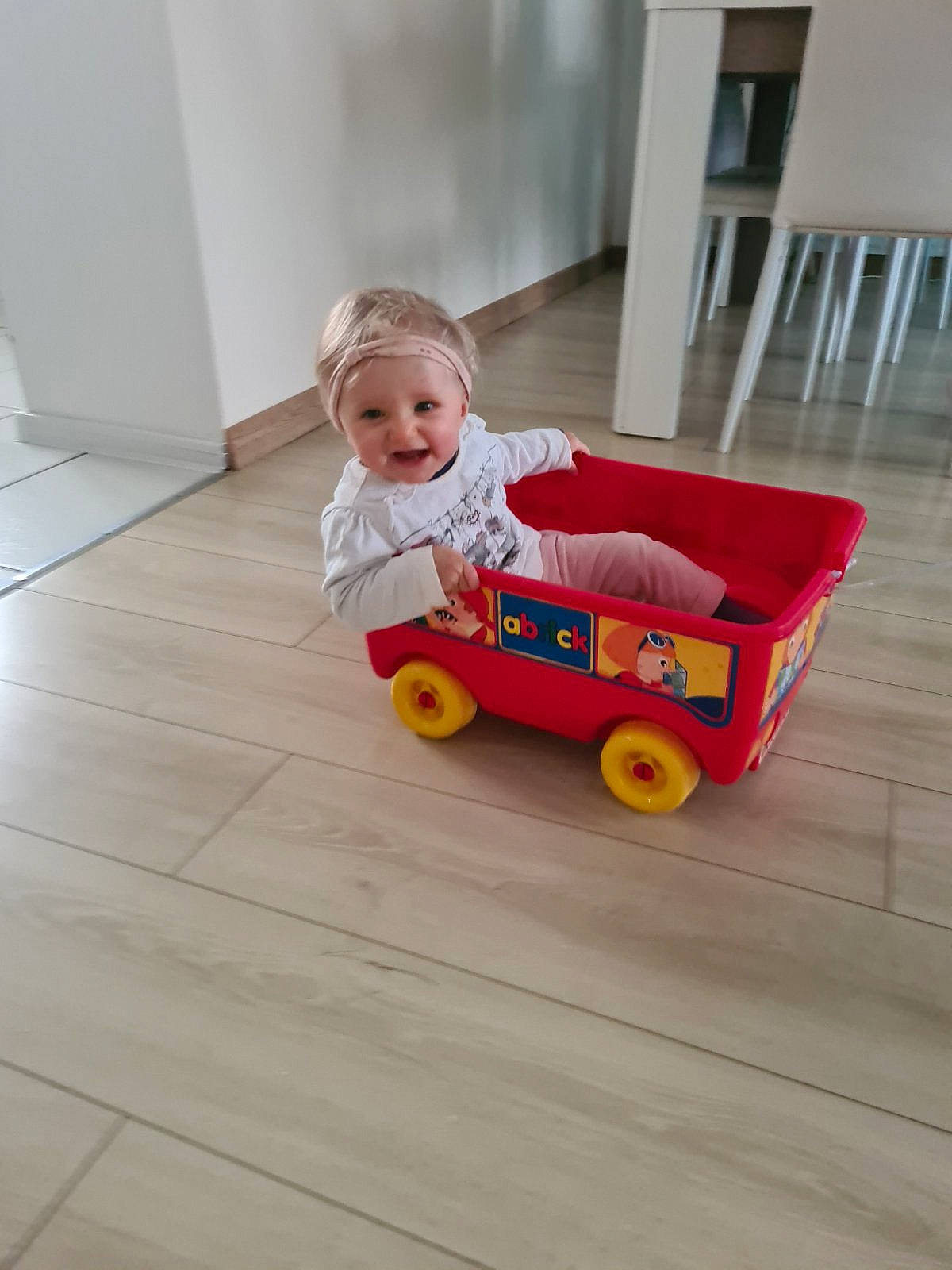 Lea participe au concours pour gagner de l'argent avec cette photo : baby, baby_products, baby_toddler_clothing, child, comfort, floor, flooring, fun, hardwood, person, room, sitting, skin, tire, toddler, varnish, vehicle, wheel, wood, wood_flooring