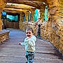 child, toddler, smile, hoodie, jeans, boots, wooden_floor, rock_wall, cave_like, aquarium_windows, glass, corridor, indoor, walking, happy, portrait, cute, young_child, family, tourist_attraction