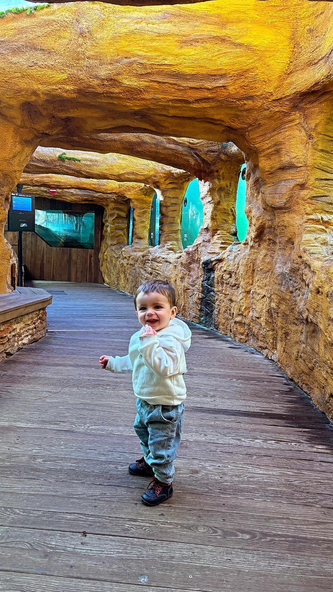 Ruben participe au concours pour gagner de l'argent avec cette photo : child, toddler, smile, hoodie, jeans, boots, wooden_floor, rock_wall, cave_like, aquarium_windows, glass, corridor, indoor, walking, happy, portrait, cute, young_child, family, tourist_attraction