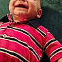 baby, smiling, child, striped_shirt, pink_clothing, navy_blue, happy, lying_down, infant, closeup, face, human, cute, young_child, buttoned_shirt, short_sleeves, skin, hand, indoors, fabric